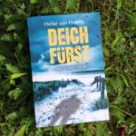 Buchcover des Buches Deichfürst. Das Buch liegt in einer Wiese.